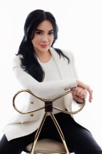 Person in white blazer seated elegantly.